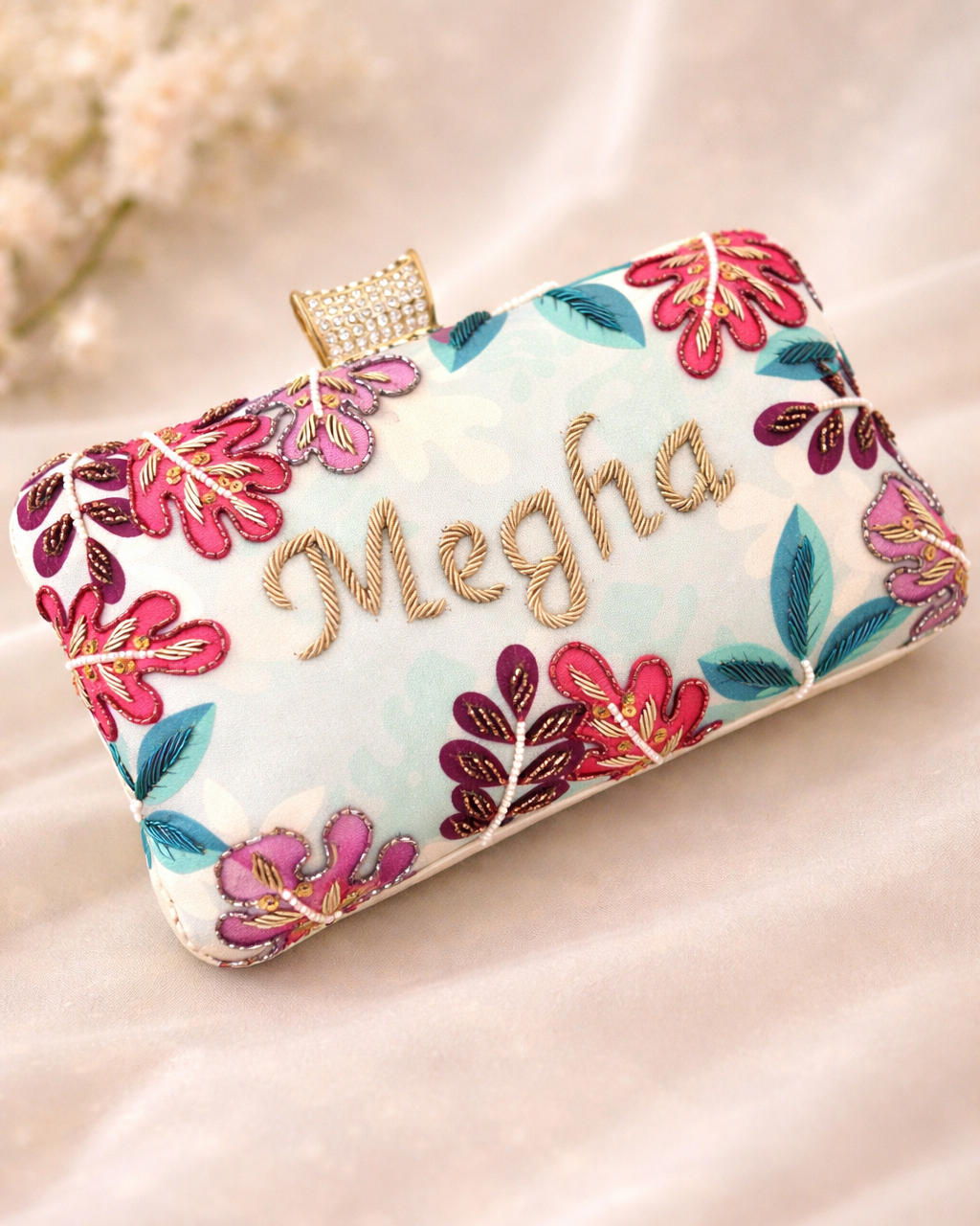 Floral embroidered clutch with 'Megha' text on a soft background