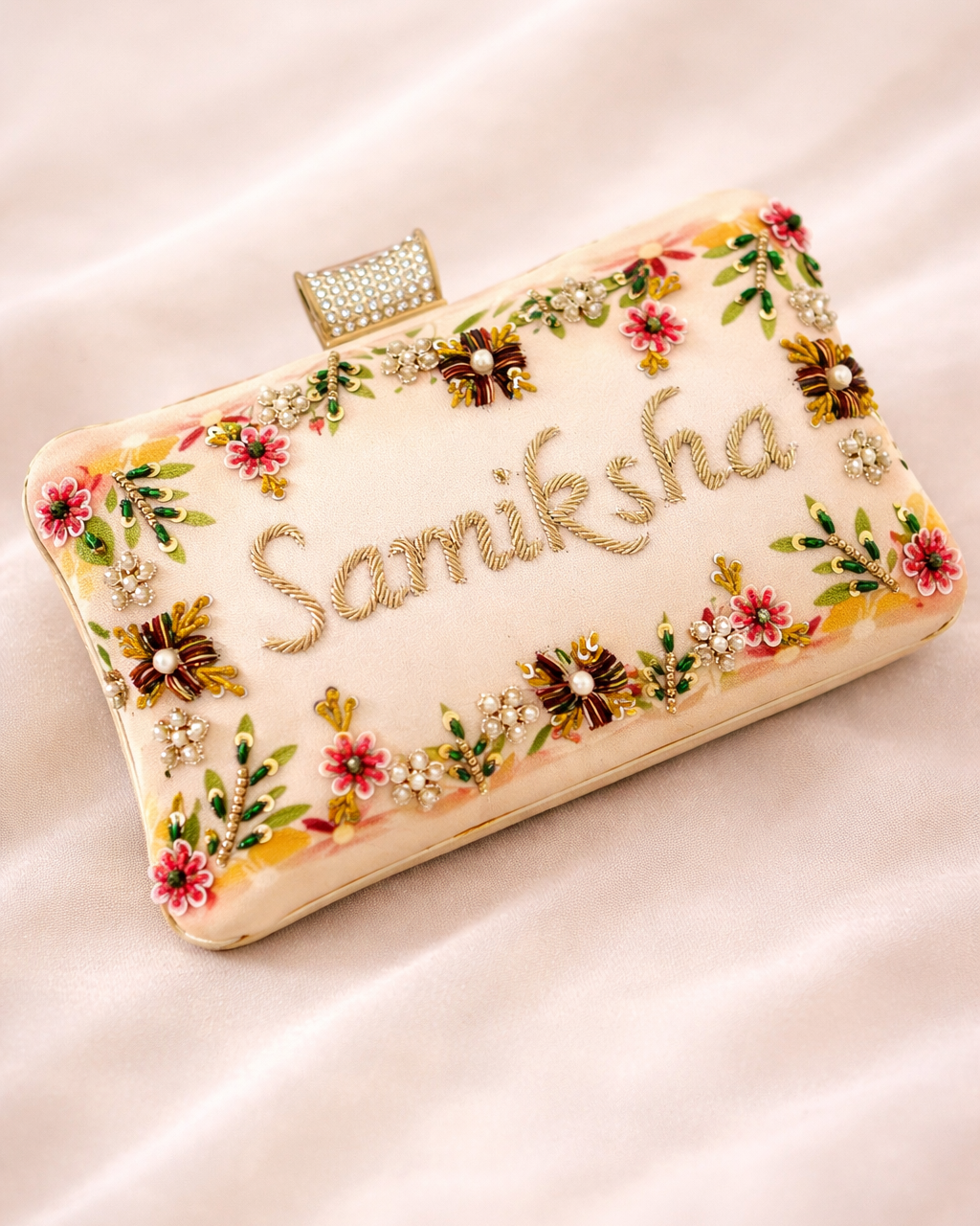 Decorative clutch with floral patterns and 'Samiksha' text on a light background