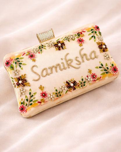 Decorative clutch with floral patterns and 'Samiksha' text on a light background