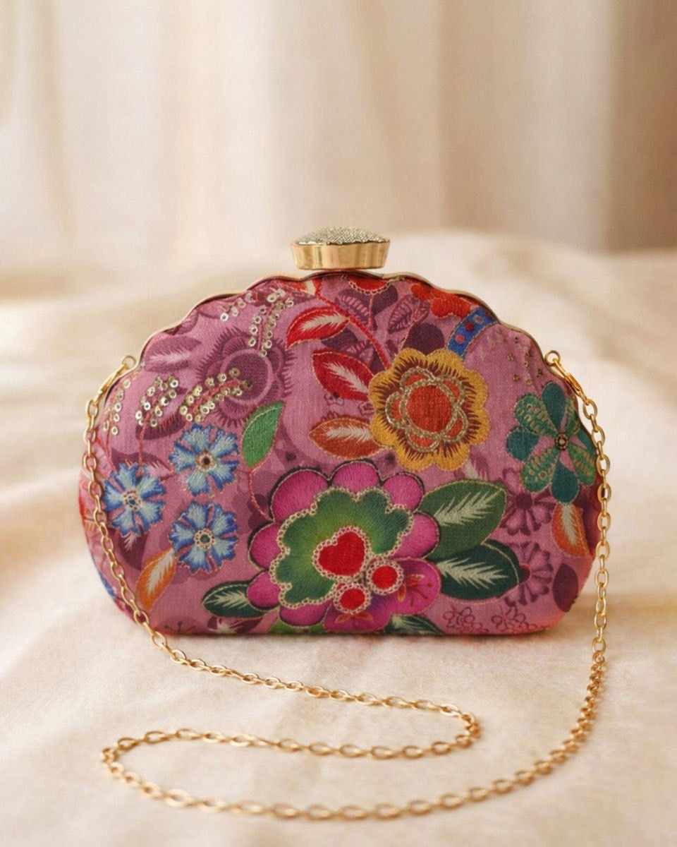 Colorful floral embroidered clutch bag with gold chain on a beige background