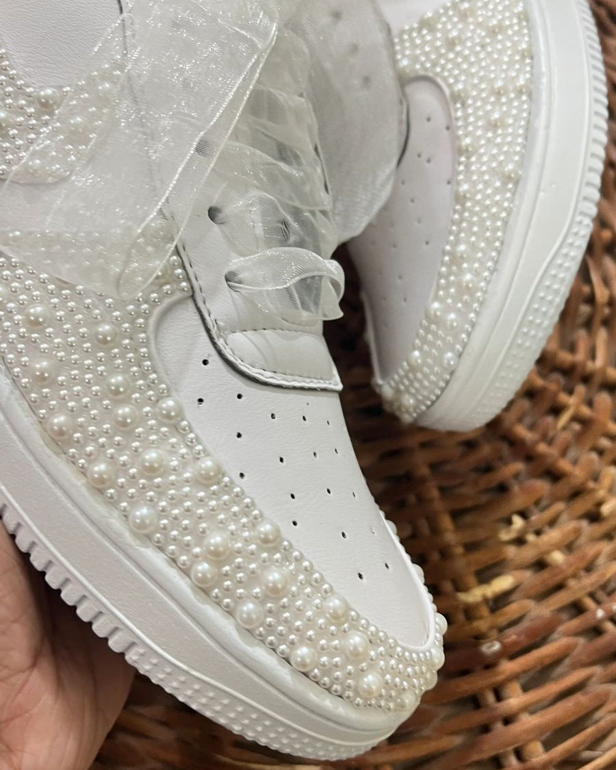 White sneakers with pearl embellishments on a woven surface
