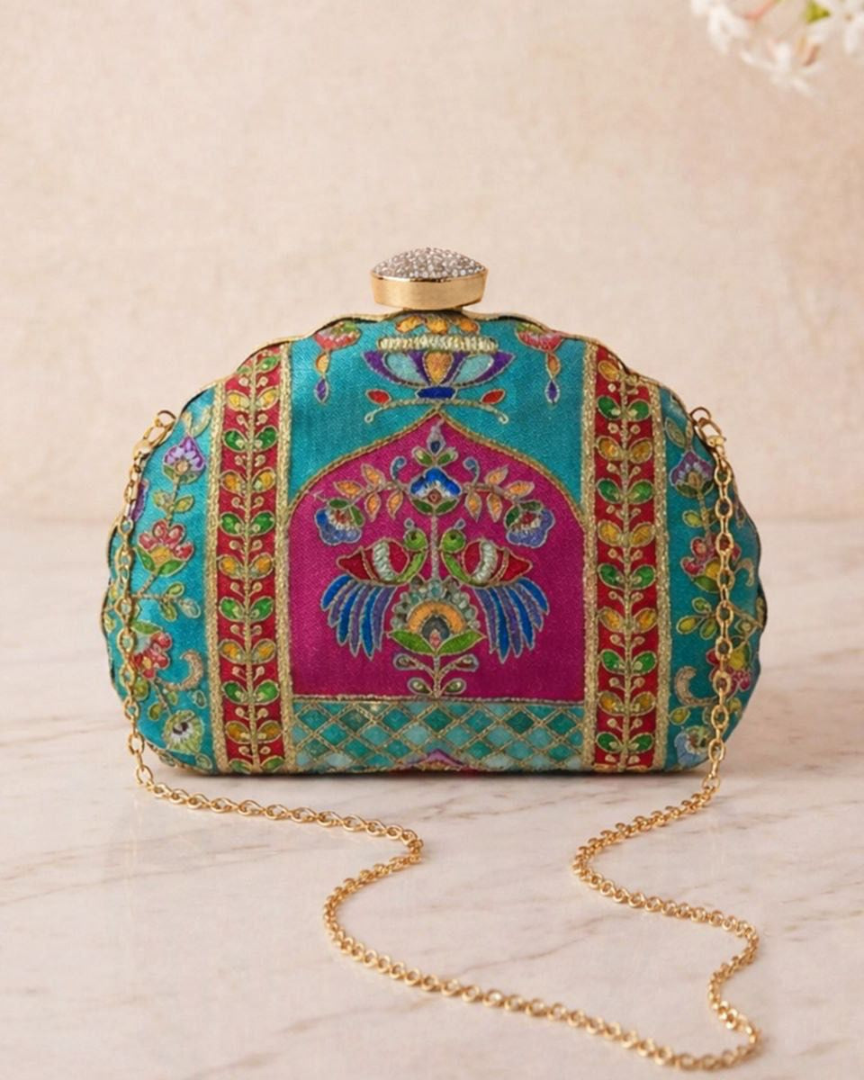 Colorful embroidered clutch bag with a gold chain on a light background