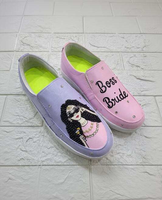 Pink and purple slip-on shoes with 'Boss Bride' text and a decorative design on a textured white background.